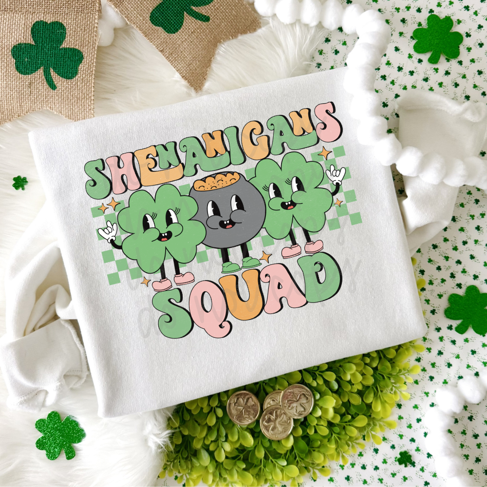 Shenanigans Squad St. Patrick’s Day graphic tee featuring three retro shamrock characters with pastel lettering on a white Bella Canvas or Comfort Colors shirt.