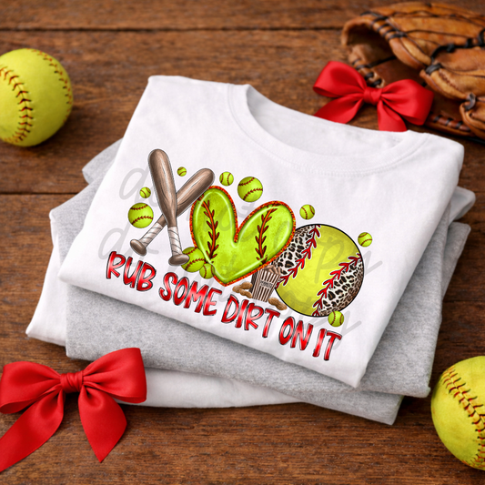Stack of folded shirts with a softball-themed design on a wooden surface with red bows and softball balls.