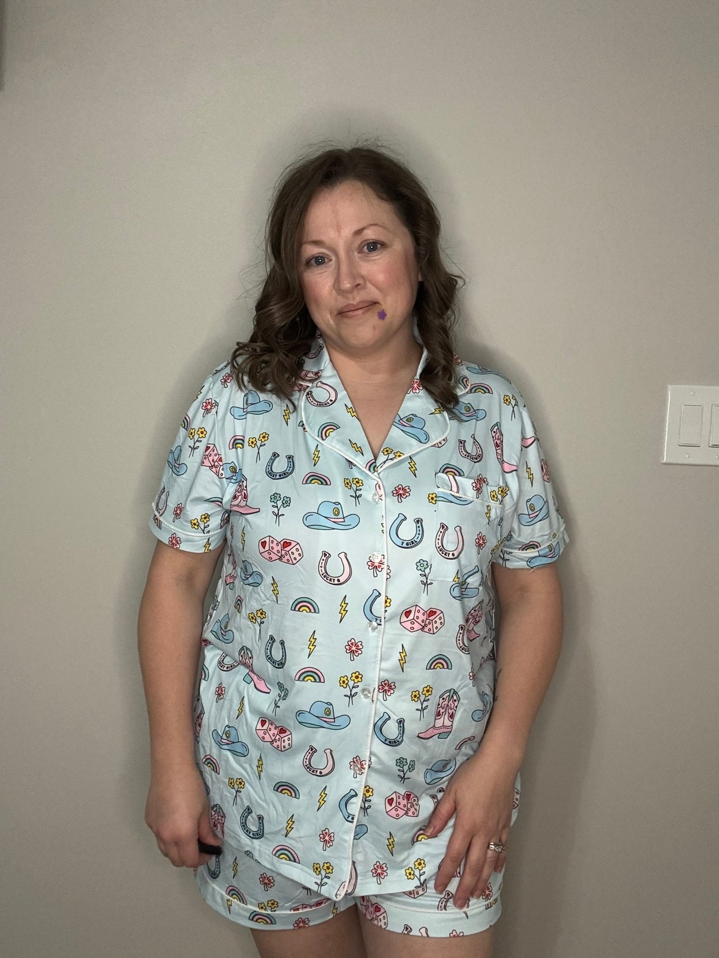 Woman wearing a cowgirl patterned pajama set against a plain wall.