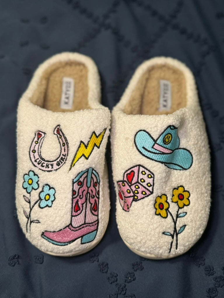 Pair of slippers with cowgirl-themed designs on a dark quilted surface